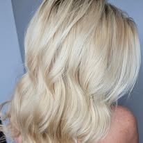 A woman with blonde hair is standing in front of a wall.