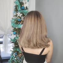 A woman with long hair is standing in front of a christmas tree.