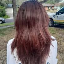 A woman with long brown hair is standing in front of a truck.