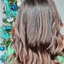 A woman with long brown hair is standing in front of a christmas tree.