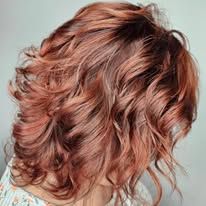 A woman with red curly hair is wearing a white shirt.