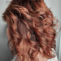 A woman with long red hair is wearing a half up half down hairstyle.