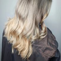 A woman with long blonde hair is wearing a black shirt.