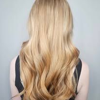 A woman with long blonde hair is wearing a black tank top.