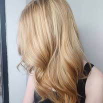 A woman with long blonde hair is wearing a black tank top.