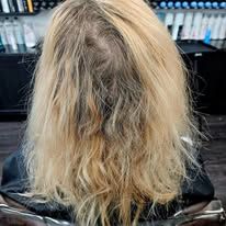 A woman with blonde hair is sitting in a chair in a salon.
