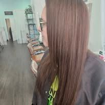 A woman with long hair and glasses is standing in a salon.