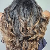 The back of a woman 's head with long wavy hair.