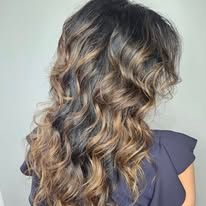 A woman with long wavy hair is wearing a black shirt.