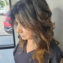 A woman with long hair is standing in front of a window.