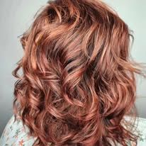 A woman with curly red hair is wearing a white shirt.