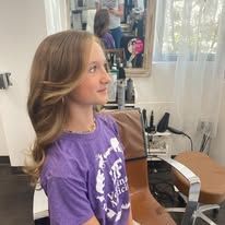 A young girl is sitting in a chair in a salon.