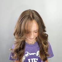 A young girl with long brown hair is wearing a purple shirt.
