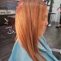 A woman with long red hair is getting her hair cut at a salon.