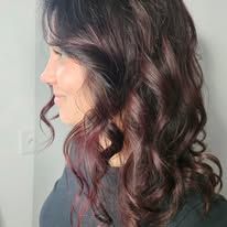 A woman with long dark hair is wearing a black shirt and smiling.