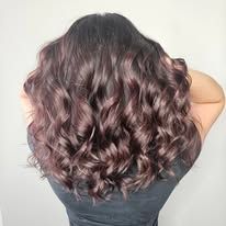 A woman with long curly hair is wearing a black shirt.