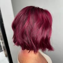 A woman with short red hair is standing in front of a mirror.