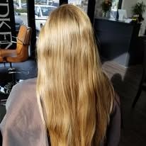 A woman with long blonde hair is sitting in a chair in a salon.