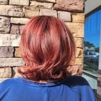 A woman with red hair is standing in front of a brick wall.
