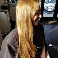 A woman with long blonde hair is sitting in a chair in a salon.