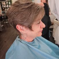 A woman is getting her hair cut at a salon.