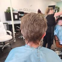 A woman is getting her hair cut in a salon.