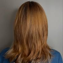 A woman with long red hair is standing in front of a wall.