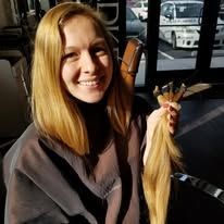 A woman is holding a bunch of hair and smiling.
