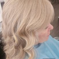 A woman with blonde hair is sitting in a chair in a salon.
