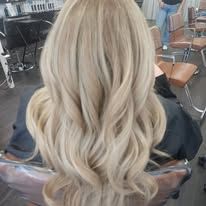A woman with long blonde hair is sitting in a chair in a salon.