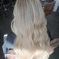 A woman with long blonde hair is sitting in a chair in a salon.