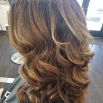 A woman with long brown hair is sitting in a chair in a salon.