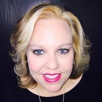 A woman with blonde hair and blue eyes is smiling for the camera.