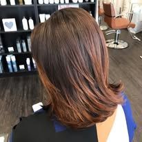 A woman is sitting in a chair with her hair in a salon.