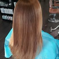 A woman with long blonde hair is sitting in a chair in a salon.