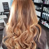 A woman with long blonde hair is sitting in a chair in a salon.