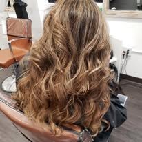 A woman with long wavy hair is sitting in a chair in a salon.