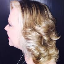 A woman with blonde hair is wearing a necklace.