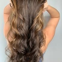 A woman with long wavy hair is wearing a braided hairstyle.