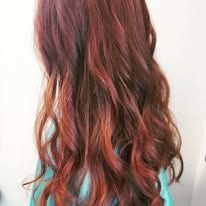 A woman with long red hair is wearing a blue shirt.