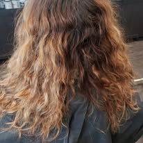 A woman with long curly hair is sitting in a chair in a salon.