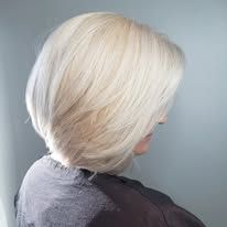 A woman with blonde hair is wearing a grey sweater and a black cape.