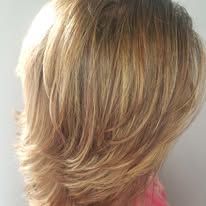 A close up of a woman 's blonde hair against a white wall.