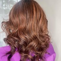 A woman with long brown hair is wearing a purple shirt.