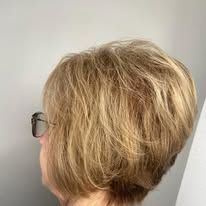A woman with short blonde hair and glasses is wearing a bob hairstyle.