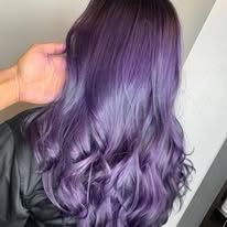 A woman with long purple hair is getting her hair dyed.