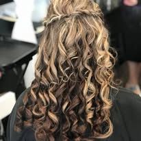 A woman with curly hair is wearing a half up half down hairstyle.