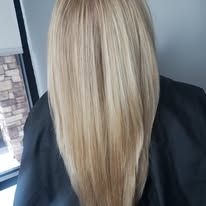 A woman with long blonde hair is sitting in front of a window.