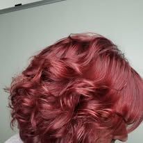 A woman with red hair is standing in front of a mirror.