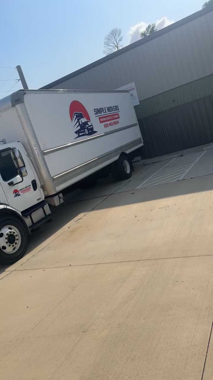 White delivery truck angled by building, side door up.